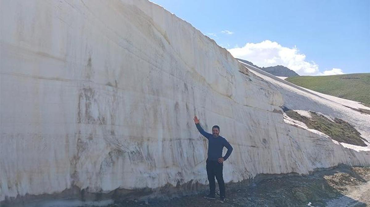 Haziran ayında Berçelan Yaylası'nda yol kenarında biriken kar yığınları ve bu manzara önünde fotoğraf çektiren insanlar.