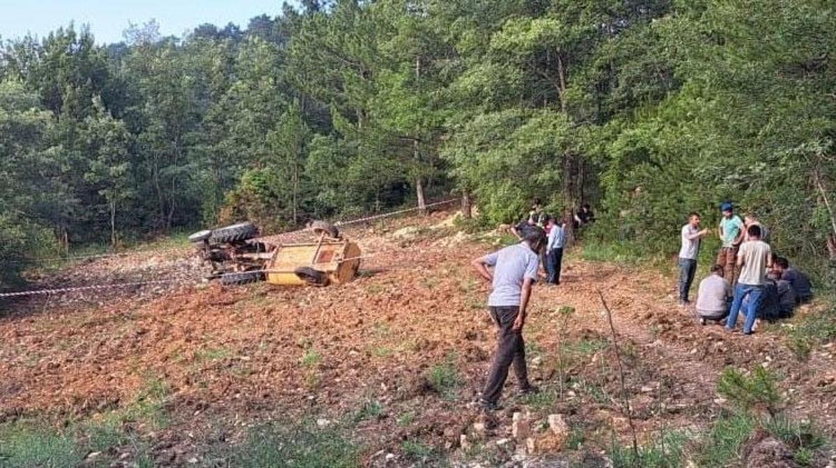 Devrilmiş bir traktörün yanında sağlık ekipleri ve olay yeri inceleme ekiplerinin çalıştığı kaza yeri.