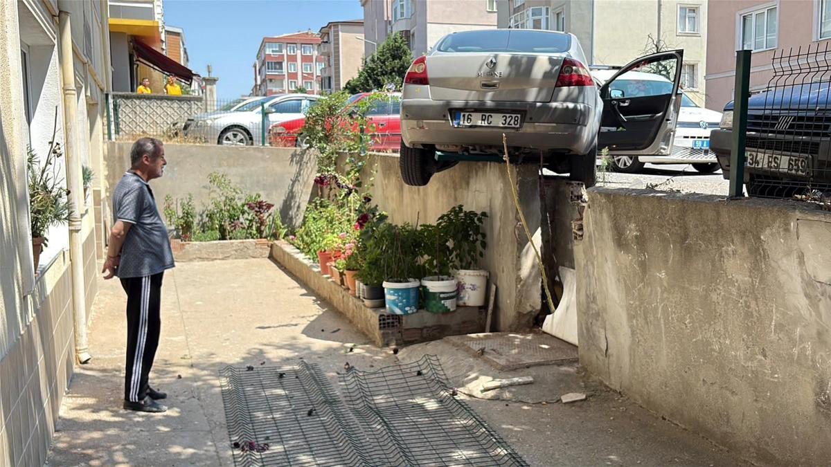 El freni çekilmeyen otomobil, hareket edip istinat duvarında asılı kaldı