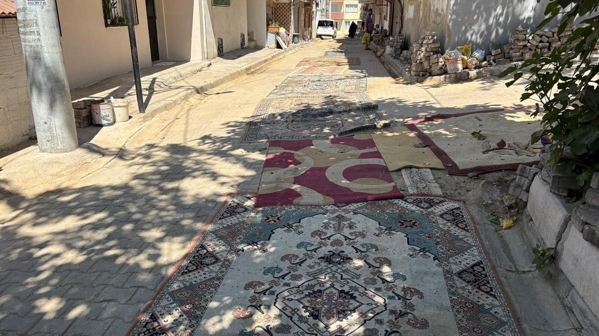 Mahalleli tozdan korunmak için onarılmayan yollara halı serdi