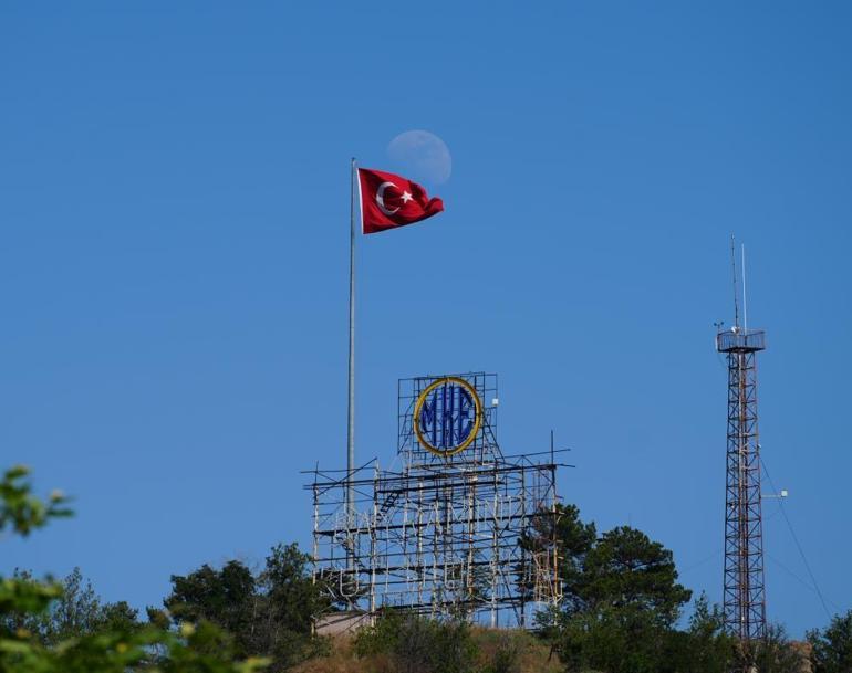 Mavi gökyüzünde dalgalanan Türk bayrağı ve ay manzarası